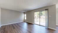 Located at 2322 Spring House Ln in Augusta, GA, this single-story unit offers three bedrooms, two bathrooms, a dedicated dining room, and a combined kitchen and living area within a efficiently arranged floor plan. Neutral-toned walls and white baseboards create a clean, cohesive aesthetic throughout.

The living room is one of the more prominent spaces, featuring dark wood-style laminate flooring, a textured ceiling, and a sliding glass door that opens to a private balcony with outdoor views of surrounding trees, allowing natural light to fill the room. A secondary window further brightens the space.

The kitchen is equipped with gray cabinetry, light stone-pattern countertops, and black appliances including a range and refrigerator, all set over matching wood-style flooring. The dining area is situated adjacent to the kitchen for convenient flow.

The bedrooms offer a mix of finishes — some feature carpet flooring while others continue the wood-style laminate — all with neutral walls and ample wall space. The primary bedroom provides a comfortable, well-proportioned retreat.

The two bathrooms include a vanity with gray cabinetry and a stone-pattern countertop paired with a large mirror, as well as a tub-shower combo with white tile surround, wood-style flooring, and accessible grab bars.