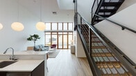 This contemporary residence showcases an impressive architectural design defined by soaring double-height ceilings and expansive floor-to-ceiling windows framed in warm wood tones. The open-plan living area is bathed in natural light, offering panoramic views of the surrounding cityscape and a shimmering waterfront beyond. Light hardwood flooring flows throughout the space, complementing the clean white walls and creating a bright, airy ambiance. A striking open-tread staircase with sleek steel railings adds a bold industrial accent to the interior.

The kitchen is thoughtfully designed with dark cabinetry, stainless steel appliances, a built-in oven, and a generous white countertop island with bar seating. Pendant globe lighting adds a warm, modern touch overhead. A dedicated dining area sits adjacent, completing the open social hub of the home.

The bedroom is a serene retreat with wood-framed windows offering urban views and ample natural light. Crisp white walls are accented with colorful artwork, adding character to the space.

The bathroom features full-height wood-look tile surround, a soaking tub with overhead rain shower, a backlit vanity mirror, and dark cabinetry — delivering a clean, spa-inspired finish throughout.