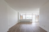Located at 35 St Dennis Dr in Toronto's Don Mills neighbourhood, this well-appointed one-bedroom, one-bathroom unit offers a thoughtfully designed layout across a single floor. Light wood laminate flooring runs throughout, creating a warm, cohesive aesthetic complemented by crisp white walls and clean-lined trim.

The open-concept living and dining area is a standout feature, anchored by expansive floor-to-ceiling windows that span an entire wall, flooding the space with natural light and framing pleasant views of surrounding greenery. A sliding door provides direct access to an outdoor area, further enhancing the connection to the outdoors. A baseboard heating system ensures year-round comfort.

The kitchen is efficiently designed with white cabinetry, dark countertops, a subway tile backsplash, and stainless steel appliances including a refrigerator and built-in microwave. A pass-through opening connects the kitchen to the living space, supporting an open flow.

The generously sized bedroom features large windows overlooking tree canopies, filling the room with natural light and tranquil views. The bathroom is finished with classic white subway tile surrounding a full soaker tub and shower combination, paired with a clean white vanity for a timeless, polished look.