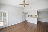 This 600-square-foot, one-bedroom, one-bathroom apartment (Design 1B #1545-206) is located at 1500 Sunbow Falls Lane in Raleigh, NC 27609. The single-floor layout is thoughtfully designed to maximize functionality within a compact footprint. The living room serves as the centerpiece of the unit, featuring dark hardwood-style flooring, neutral gray walls, a tile-surround fireplace, and multiple windows with horizontal blinds that allow natural light to filter in, along with a sliding glass door opening to an outdoor view. The galley-style kitchen is well-equipped with white cabinetry, granite-look countertops, black and stainless steel appliances including an electric range, refrigerator, and dishwasher, complemented by hardwood-style flooring throughout. The 150-square-foot bedroom offers plush carpeting, a sliding glass door with vertical blinds providing outdoor access, and direct entry to a closet and an in-unit laundry area with washer and dryer hookups. The bathroom features white cabinetry, a single-basin vanity with a granite-look countertop, a large mirror, and a full tub-shower combo with tile surround. Textured ceilings are consistent throughout the unit.