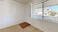 Located at 5025 N First Ave in Tucson, Arizona, this one-bedroom, one-bathroom unit offers a practical and efficient single-floor layout. The living area welcomes you with carpeted flooring, a ceiling fan with light fixture, and a large sliding window beside the front entry door that fills the space with natural light and offers views of mature trees outside. The open layout connects the living area to the kitchen, which features a galley-style design with warm wood-toned cabinetry lining both sides, white laminate countertops, a stainless steel sink, a white electric range, and a black refrigerator — all set atop wood-look vinyl flooring. The bedroom is a comfortable, carpeted room with a sliding window framed by louvered shutters, allowing ample natural light and outdoor views. A closet provides dedicated storage. The bathroom is outfitted with wood-look vinyl flooring, a single vanity with sink, a toilet, and a full tub and shower combination with a tile-surround enclosure. Throughout the unit, textured ceilings and clean white walls create a neutral, move-in-ready atmosphere well-suited for efficient, low-maintenance living in Tucson.