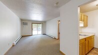 Located at 2824 Grand Ave in Des Moines, Iowa, this 2-bedroom, 1-bathroom unit offers a practical and well-organized single-floor layout. The living area features neutral carpet flooring and crisp white walls, with baseboard heating running along the perimeter to ensure consistent warmth. A wood-framed entry door opens into a hallway that connects the main living spaces efficiently.

The generously sized primary bedroom includes a wall-mounted air conditioning unit, baseboard heating, and a textured ceiling, providing year-round climate control. The second bedroom features a ceiling fan with light fixture, two windows with wood trim that allow natural light to filter in, and the same comfortable carpet flooring.

The kitchen is outfitted with warm oak cabinetry offering ample upper and lower storage, light countertops, a stainless steel sink, and tile flooring. A separate door within the kitchen leads to additional storage or utility access. The layout is compact yet functional, with a range included.

The bathroom features tile flooring, a wood-trimmed vanity with a sink, and a full tub-and-shower combination finished with classic white subway tile, accented by chrome fixtures and towel bars. Overall, the unit presents a clean, straightforward living environment suited for practical, comfortable everyday living.