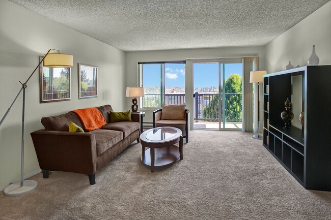 A spacious living room with two sliding glass doors that lead out to the private balcony - Arrive Magnolia