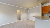 Located at 6443 Zebulon Rd in Macon, Georgia, this single-story, one-bedroom, one-bathroom unit offers a practical and well-organized layout across a compact yet efficiently designed floor plan. The interior is finished with neutral warm-gray and beige tones throughout, contributing to a clean, cohesive aesthetic.

The living room is carpeted and features crown molding, a ceiling fan, and access to an exterior door flanked by windows that allow natural light to fill the space. A pendant chandelier adds a decorative touch near the kitchen transition area. The kitchen is laid out in a galley configuration, featuring warm honey-toned wood cabinetry, granite-style countertops, dark hardwood-style flooring, a double sink, and black appliances including a range and refrigerator.

The bedroom is carpeted and includes crown molding, a ceiling fan, and a window offering outdoor views, providing a comfortable and well-lit retreat. A dedicated closet provides organized storage. The bathroom includes a full tub-shower combination with built-in shelving, wood-style flooring, and a vanity with a granite-style countertop. Three hallways connect the rooms, ensuring smooth circulation throughout the unit.
