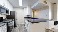 Located at 2235 W Broadway in Anaheim, CA, this one-bedroom, one-bathroom residence offers a thoughtfully designed single-floor layout that maximizes every square foot. The open-concept living, dining, and kitchen area serves as the heart of the home, seamlessly connecting daily living spaces. The kitchen is well-appointed with crisp white cabinetry, dark countertops, a stainless steel refrigerator, gas range, and built-in microwave, all set atop wood-look flooring with a skylight overhead that fills the space with natural light. A peninsula with a sink adds both functionality and a subtle division between the kitchen and the combined living and dining area. The living room features soft carpeting, a ceiling fan, a fireplace, and sliding glass doors that open onto a private patio, bringing in natural light and outdoor access. The spacious bedroom offers comfortable carpeted flooring, a sliding glass door with patio access, and a generously sized closet for ample storage. An additional closet provides further organizational convenience. The full bathroom includes a soaking tub and shower combination in a clean, all-white finish. Neutral tones and a textured ceiling carry throughout the unit, giving the space a cohesive, understated character.