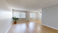 Located at 8828 Highland Ave in Whittier, CA, this single-story unit offers a thoughtfully organized layout comprising a living room, bedroom, kitchen, and hallway. The living room is generously proportioned, featuring light-toned hardwood-style flooring, a textured ceiling, and multiple windows fitted with vertical blinds that allow abundant natural light to fill the space. A ceiling fan with integrated lighting provides both comfort and illumination, while a wall-mounted air conditioning unit ensures climate control. Built-in shelving along one wall offers practical storage and display options, adding a functional design element to the room. The kitchen is cleanly appointed with white cabinetry, gray countertops, subway tile backsplash, and stainless steel appliances including a refrigerator and dishwasher, all set on light wood-style flooring. The bedroom is a spacious retreat finished with plush carpeting, a window with vertical blinds, and a full-width mirrored sliding closet that enhances the sense of space. Neutral gray tones carry throughout the unit, creating a cohesive and modern aesthetic. A hallway connects the main living areas, completing the efficient and comfortable floor plan of this Whittier residence.