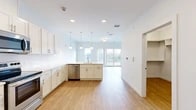 Located at 109 Air City Blvd in Rome, NY, this single-floor studio unit offers a well-designed open-concept layout that efficiently combines the kitchen and living areas into one cohesive space. Light-toned hardwood-style flooring runs throughout, contributing to a clean, contemporary aesthetic enhanced by crisp white walls and recessed lighting.

The kitchen is a standout feature, equipped with white shaker-style cabinetry extending to the ceiling for ample storage, bright white countertops, and a full suite of stainless steel appliances including a range, over-the-range microwave, refrigerator, and dishwasher. A peninsula with pendant lighting defines the kitchen zone while maintaining an open connection to the living area.

The living area benefits from generous natural light, courtesy of large sliding glass doors that open to a private balcony offering outdoor views. Additional windows along the perimeter further enhance the bright, airy atmosphere of the space.

The bathroom is finished in clean white tones and includes a tub-shower combination with chrome fixtures. A dedicated closet provides practical storage, while the entrance offers a clear transition into the main living space. Overall, the unit presents a modern, functional environment well-suited for efficient single-occupant living.