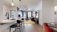 This single-story, two-bedroom, two-bathroom residence in Birmingham, Alabama offers a thoughtfully designed open-concept floor plan that maximizes functionality and style. Wood-style flooring flows throughout the main living areas, anchoring the space with warmth and continuity.

The living room serves as a central gathering point, highlighted by a bold navy accent wall, ceiling fan, and a glass door that introduces natural light and outdoor access. The kitchen features gray shaker-style cabinetry with matte black hardware, stainless steel appliances, a white subway tile backsplash, light countertops, and a center island with pendant lighting and bar seating. A dedicated dining area nearby includes built-in open shelving, adding both storage and character.

The primary bedroom features a distinctive textured accent wall, natural light from a window, a ceiling fan, and direct access to a walk-in closet. Its en-suite bathroom offers a glass-enclosed shower, a single vanity with gray cabinetry, and direct closet access. The second bedroom also provides walk-in closet space, while the second bathroom includes a tub-shower combo, a framed mirror, and a gray vanity with ample storage.