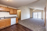 This single-floor residence is thoughtfully designed with a functional, open layout that seamlessly connects the kitchen and living areas. The kitchen is well-appointed with warm oak cabinetry offering generous storage, dark laminate countertops, and a full suite of white appliances including a refrigerator, range, built-in microwave, and dishwasher. Rich, dark hardwood-style flooring grounds the kitchen space, transitioning into plush carpeting in the expansive living area. The living room benefits from soaring vaulted ceilings, a ceiling fan, and a sliding glass door that invites natural light and outdoor views.

The bedrooms are comfortably sized, each featuring soft carpeting, neutral walls, and large multi-pane windows that frame outdoor scenery and fill the rooms with natural light. Two full bathrooms serve the unit, each equipped with a shower/tub combination, vanity with wood cabinetry, and durable hardwood-style flooring. Textured ceilings are present in select areas, adding subtle architectural detail. Throughout the residence, warm-toned wood trim and baseboards provide a cohesive, classic finish. The overall ambiance is clean, bright, and move-in ready, offering a practical and comfortable living environment.