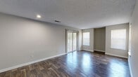 Located at 1507 Pine Dr in Atlanta, GA, this single-floor, one-bedroom, two-bathroom home offers a practical and well-organized layout. Dark hardwood-style flooring flows throughout the main living areas, complemented by neutral gray walls and textured ceilings that lend a clean, consistent aesthetic.

The living room is bright and open, featuring a sliding glass door with vertical blinds that allows natural light to pour in and provides outdoor views. Multiple windows further enhance the airy feel of the space. The kitchen is efficiently designed in a galley style, outfitted with dark espresso cabinetry, gray laminate countertops, a double stainless steel sink, and black appliances including a range and refrigerator. A tile backsplash adds a decorative touch, and a closet provides additional storage.

The bedroom is comfortably sized, featuring plush carpeting, a ceiling fan with a light fixture, and a sliding glass door offering outdoor access and natural light. Two bathrooms serve the home — one includes a vanity with dark cabinetry and a gray countertop, while the second is a dedicated water closet. A connecting hallway ties the layout together efficiently, making this home a functional and comfortable space.