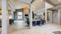 Located at 1 Landau Blvd in Ballston Spa, NY, this generously sized community clubhouse offers a thoughtfully designed single-floor layout encompassing a wide variety of amenity spaces. The centerpiece is a grand open-plan living and dining area defined by soaring vaulted ceilings, structural columns, and large windows that flood the space with natural light. A dramatic floor-to-ceiling stone fireplace serves as the focal point of the living area, complemented by contemporary globe chandeliers and large-format tile flooring. A long communal dining table anchors the adjoining dining zone, while a built-in open shelving unit adds a stylish, functional accent.

A second dining and kitchen area features stainless steel appliances, custom cabinetry, a breakfast bar, and hardwood-style flooring, opening to a casual lounge with a pool table and a rustic wood-paneled ceiling. A cozy living room with leather furnishings and a reclaimed wood ceiling offers a more intimate retreat. The dedicated office provides workstation seating, ample natural light, and curated artwork. The well-equipped fitness center includes cardio machines, free weights, and wall-to-wall mirrors. Completing the space is an indoor pool area with high ceilings, poolside seating, and direct access to changing rooms.