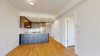 Located at 803 Village Dr in Port Coquitlam, BC, this well-appointed one-bedroom, one-bathroom unit offers a thoughtfully designed open-concept layout across a single floor. Light hardwood flooring flows throughout the living spaces, complementing the clean white walls and recessed lighting that give the interior a bright, modern feel.

The kitchen is a standout feature, showcasing rich wood-toned cabinetry that extends to the ceiling, a granite-topped island with an integrated double sink, stainless steel appliances including a refrigerator and dishwasher, and a white tile backsplash. The kitchen opens seamlessly into the dining and living area, which benefits from large floor-to-ceiling windows that flood the space with natural light and offer views of the surrounding neighbourhood.

A sliding glass door leads to a private balcony, extending the living space outdoors. The bedroom is a comfortable, well-lit room with large windows framing outdoor views, hardwood flooring, and direct access to the balcony. A dedicated closet provides practical storage.

The bathroom is finished in a clean, contemporary style with large-format white tile flooring, a wood-toned vanity with an undermount sink, a wide mirror, and chrome fixtures. A separate closet completes this efficiently designed residence.