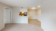 This single-floor residence offers a practical and comfortable layout designed for everyday living. The living area is finished with plush carpeting and neutral-toned walls, and features a sliding glass door with vertical blinds that opens to a private balcony, filling the space with natural light and providing pleasant outdoor views. An adjoining area with light wood-style flooring connects seamlessly to the kitchen, which is designed in a galley configuration equipped with stainless steel appliances including a refrigerator and stove, white cabinetry, a countertop sink, and track lighting overhead. A pass-through counter opening connects the kitchen to the living space, enhancing the open feel of the home. The bedroom is generously sized, also carpeted, and features a textured ceiling. It benefits from direct access to both a walk-in closet with built-in shelving and a full bathroom. The bathroom is finished with white tile surrounding a tub-shower combination, an overhead storage cabinet, a granite-style countertop with sink, and a large vanity mirror with overhead lighting. Throughout the residence, neutral color palettes and consistent finishes create a cohesive and inviting atmosphere.