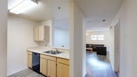 Located at 101 Legacy Ter in Chapel Hill, NC, this single-floor home offers three bedrooms and two full bathrooms within a practical, well-organized layout. The open-concept kitchen features light wood cabinetry, white laminate countertops, a double-basin stainless steel sink, and black appliances including a refrigerator, range, microwave, and dishwasher. A pass-through counter connects the kitchen to the adjoining dining and living areas, creating a cohesive shared space. The living room is finished with durable wood-look flooring and is brightened by a window with natural light, complemented by a ceiling fan overhead. The dining area provides a defined space adjacent to the living room, also with wood-look flooring. The three bedrooms feature carpet flooring and ceiling fans, with the primary bedroom offering a closet with mirrored doors and a window with outdoor views. Both bathrooms include a full tub-shower combination with clean white surrounds and chrome fixtures. A dedicated laundry room houses a full-size washer and dryer alongside the water heater and electrical panel, adding functional utility to the home. The overall aesthetic is clean, neutral, and practical throughout.