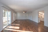 Located in Marietta, Georgia, this single-floor residence at Waterfall Village offers a well-organized layout with consistent design choices throughout. Rich, dark hardwood-style flooring runs seamlessly across the living areas, bedrooms, and hallways, creating a cohesive and polished aesthetic.

The open entry leads into a generously sized living area bathed in natural light, with sliding glass doors fitted with vertical blinds that provide access to the outdoors. A long central hallway connects the main living spaces to the private rooms, giving the layout a clear and functional flow.

The kitchen has been thoughtfully updated with white cabinetry featuring black hardware, light stone-look countertops, a marble-style backsplash, and stainless steel appliances including a dishwasher and refrigerator. A louvered closet door hints at additional storage nearby.

The bedrooms are well-proportioned, each featuring ceiling fans with integrated lighting, vertical blind-covered windows that invite natural light, and views of surrounding greenery. Closet access is conveniently located near the bedrooms.

The bathroom is cleanly appointed with a combination tub and shower, a vanity with granite-style countertops, a large mirror, and warm neutral tones throughout. The textured ceilings in select areas add a subtle architectural detail to this tidy, move-in-ready home.