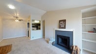 This single-floor residence offers a thoughtfully designed layout that balances comfort and functionality. The living area serves as the heart of the home, highlighted by vaulted ceilings that lend a sense of openness and airiness to the space. Plush wall-to-wall carpeting adds warmth underfoot, while neutral toned walls create a clean and inviting backdrop throughout. A standout feature of the living room is the tile-surround fireplace with a crisp white mantle, providing a natural focal point and a cozy atmosphere. A convenient pass-through window connects the living area to the kitchen, enhancing the open feel and allowing for easy interaction between spaces. The kitchen is equipped with dark cabinetry, stainless steel appliances, and overhead lighting, offering a practical and stylish cooking environment. The overall ambiance of the space is calm and welcoming, with a simple, classic aesthetic that provides an excellent foundation for personalization. The single-floor design ensures easy accessibility and a seamless flow from one area to the next, making this a comfortable and livable home.