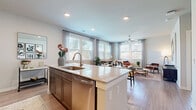 This single-floor residence features 2 bedrooms and 2 bathrooms, thoughtfully arranged across a comfortable and functional floor plan. The open-concept kitchen and living area serves as the heart of the home, where a large granite-topped island with an undermount sink and stainless steel appliances anchors the kitchen. Dark cabinetry reaching to the ceiling provides generous storage, while light wood-style flooring extends seamlessly throughout the space. The living room is bathed in natural light from multiple windows dressed with sheer curtains, and a ceiling fan adds to the airy, comfortable atmosphere. The primary bedroom is a well-proportioned retreat with a window overlooking the outdoors, complemented by easy access to a dedicated closet outfitted with wire shelving systems for organized storage. The bathrooms are finished with granite vanity countertops, dark cabinetry, and classic white subway tile surrounding a soaking tub and shower combination. A central hallway connects the bedrooms and bathrooms, lined with clean white panel doors — including a louvered closet door — and recessed lighting overhead. Neutral wall tones and consistent light wood flooring throughout create a cohesive, modern aesthetic that is both inviting and practical.