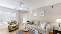 Located in Kissimmee, Florida, this single-story residence offers a thoughtfully designed layout that balances comfort and functionality throughout. The living room serves as the heart of the home, featuring warm neutral-toned walls, plush carpeting, and abundant natural light streaming through large windows dressed with horizontal blinds. A ceiling fan overhead and a private exterior door add to the room's practicality and airiness.

The galley-style kitchen is outfitted with white cabinetry, white appliances including a range, refrigerator, microwave, and dishwasher, all complemented by wood-look flooring that extends through the corridor. A dedicated dining area adjacent to the main living space features a pendant light fixture above a glass-top table, creating a defined yet open setting for meals.

The primary bedroom is a serene retreat with soft carpeting, a ceiling fan, a soothing blue accent wall, and a generous closet. A secondary bedroom mirrors this comfortable aesthetic with similar finishes and a large window that invites natural light.

The bathrooms are clean and functional: one features a full-size soaking tub with tiled surround and decorative shower curtain, while the other offers a single-sink vanity with ample counter space and tile flooring. The overall ambiance throughout the residence is calm, cohesive, and move-in ready.
