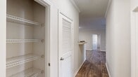Located at 2350 Houston Lake Rd in Perry, Georgia, this well-appointed 2-bedroom, 2-bathroom single-story home offers a thoughtfully designed layout across a comfortable footprint. The interior features wood-look hardwood flooring throughout the main living areas, complemented by neutral-toned walls and clean white trim that lend a bright, cohesive aesthetic.

The galley-style kitchen is equipped with warm-toned wooden cabinetry extending to the ceiling for generous storage, black appliances including a refrigerator and range, and a single-basin sink with ample counter space. The kitchen flows naturally into the rest of the home via a central hallway accented with crown molding.

The hallway also provides access to a linen closet fitted with wire shelving for organized storage. Each bedroom features plush carpeting and dedicated walk-in closets outfitted with multi-level wire shelving systems, providing practical and abundant storage. The primary bedroom is generously sized with its own closet. The secondary bedroom benefits from a window that invites natural light into the space.

Both bathrooms are cleanly finished, with one featuring a full soaking tub and shower combination surrounded by white tile. Ceiling fans are present in the main living areas, and crown molding details add a refined touch throughout this move-in-ready home.