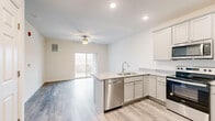 Located at 150 Panay Way in Winchester, Virginia, this thoughtfully designed one-bedroom, one-bathroom residence offers a clean, modern aesthetic with consistent wood-style flooring flowing throughout every room. The open-concept living and kitchen area forms the heart of the home, anchored by a peninsula with granite-style countertops, an undermount sink, and built-in power outlets. The kitchen is fully equipped with stainless steel appliances — including a refrigerator, range, microwave, and dishwasher — and features soft gray cabinetry with ample upper and lower storage. Recessed lighting and a ceiling fan keep the living area bright and comfortable, while a sliding glass door opens to an outdoor space, inviting natural light and fresh air. The spacious primary bedroom accommodates generous furnishings and is served by a dedicated walk-in closet outfitted with wire shelving systems for organized storage. The bathroom is finished with a stand-alone shower, a vanity with storage, and coordinating wood-style flooring. Neutral wall tones and clean finishes create a bright, cohesive atmosphere throughout, making this residence a comfortable and functional home in Winchester, VA.