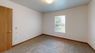 Located in Shawnee, Kansas, this two-bedroom, one-bathroom unit offers a practical and well-organized layout across a single floor. The kitchen features white cabinetry with warm wood trim accents, light countertops, a built-in dishwasher, and wood-look vinyl flooring, with direct access to a walk-in pantry or closet equipped with wire shelving — a convenient touch for added storage. The bathroom is finished with matching wood-trimmed cabinetry, a single vanity, and wood-look vinyl flooring, and includes accessibility-friendly grab bars near the toilet. Both bedrooms are carpeted and bathed in natural light from windows overlooking greenery. The primary bedroom is generously sized and connects to a dedicated walk-in closet outfitted with wire shelving and hanging rods, offering ample storage. The second bedroom features a sliding wood-panel closet door and its own window view. A connecting hallway ties the rooms together seamlessly. Neutral wall tones and warm wood baseboards throughout the unit create a clean, cohesive aesthetic. The overall layout is efficient and well-suited for comfortable everyday living.