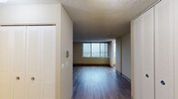 Located at 5441 N East River Rd in Chicago's northwest side, this well-organized single-floor unit offers a functional layout comprising a living room, kitchen, and bathroom. The living area is generously proportioned for its footprint, featuring durable hardwood-style flooring in a warm gray tone, neutral beige walls, and large sliding glass doors that open to a private balcony with expansive outdoor views of the surrounding cityscape. Multiple windows throughout the space invite abundant natural light, creating an airy and open ambiance. The kitchen is efficiently designed with white cabinetry extending to the ceiling for ample storage, a built-in countertop workspace, light wood-style flooring, a gas range, and a full-size refrigerator. A ventilation hood is integrated above the stove, and a large window adds brightness to the cooking area. The sleeping or flex space includes a built-in closet with full-height white panel doors, providing practical storage. The bathroom is fitted with a classic tiled tub-and-shower combination, featuring clean white square tiles and chrome fixtures. Throughout the unit, consistent flooring and a neutral color palette create a cohesive and move-in-ready environment.