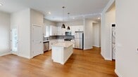 Located on N Ernston Rd in Sayreville, NJ, this well-appointed 2-bedroom, 2-bathroom single-story home offers a thoughtfully designed layout across a comfortable footprint. A welcoming entrance leads into an open-concept living, dining, and kitchen area bathed in natural light from multiple windows. The kitchen is a standout feature, showcasing crisp white shaker cabinetry, a subway tile backsplash, a center island with a quartz countertop, stainless steel appliances including a refrigerator, gas range, microwave, and dishwasher, and stylish pendant lighting overhead. Warm hardwood flooring flows throughout the main living areas, adding a cohesive and polished feel. The generously sized primary bedroom features plush carpeting, multiple windows, and access to a spacious walk-in closet with wire shelving. The second bedroom is equally well-lit with hardwood floors and its own closet. Both bathrooms are elegantly finished; one features a glass-enclosed walk-in shower with white subway tile and matte black fixtures. Additional highlights include a laundry area, a pantry, abundant closet storage throughout, and a private patio. The neutral color palette and modern finishes create a clean, contemporary ambiance throughout.