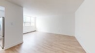 Located at 120 Dundas St E in Mississauga, this one-bedroom, one-bathroom unit offers a well-organized layout across a single floor. Light-toned hardwood flooring runs throughout the main living areas, creating a warm and cohesive feel. The open hallway entry connects seamlessly to the living and dining area, a generously sized space bathed in natural light from large windows that frame views of the surrounding urban neighbourhood. Baseboard heating units are found throughout, ensuring year-round comfort. The kitchen is efficiently designed with a galley-style layout, featuring white cabinetry, dark countertops, a tiled backsplash, large-format tile flooring, and stainless steel appliances including a full-size refrigerator. A window above the counter brings in additional natural light. The bedroom offers a comfortable footprint, mirrored sliding closet doors, a window with outdoor views, and direct access to the hallway. The bathroom is finished with classic white subway tile surrounding the soaker tub and shower, a vanity with under-sink storage, and neutral tile flooring. Overall, the unit presents a clean, bright, and functional living space with a modern, minimalist aesthetic.