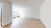 Located at 120 Dundas St E in Mississauga, this one-bedroom, one-bathroom unit offers a well-organized layout across a single floor. Light-toned hardwood flooring runs throughout the main living areas, creating a warm and cohesive feel. The open hallway entry connects seamlessly to the living and dining area, a generously sized space bathed in natural light from large windows that frame views of the surrounding urban neighbourhood. Baseboard heating units are found throughout, ensuring year-round comfort. The kitchen is efficiently designed with a galley-style layout, featuring white cabinetry, dark countertops, a tiled backsplash, large-format tile flooring, and stainless steel appliances including a full-size refrigerator. A window above the counter brings in additional natural light. The bedroom offers a comfortable footprint, mirrored sliding closet doors, a window with outdoor views, and direct access to the hallway. The bathroom is finished with classic white subway tile surrounding the soaker tub and shower, a vanity with under-sink storage, and neutral tile flooring. Overall, the unit presents a clean, bright, and functional living space with a modern, minimalist aesthetic.