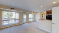 This single-floor residence offers a thoughtfully designed open-concept layout that seamlessly connects the living, dining, and kitchen areas. The spacious living room is carpeted and bathed in natural light, courtesy of large windows and a glass door that opens directly onto a private balcony, providing outdoor views of the surrounding neighborhood. Recessed lighting throughout adds to the bright, welcoming atmosphere.

The kitchen is well-appointed with warm-toned wood cabinetry, granite countertops, black appliances including a gas range, over-the-range microwave, and refrigerator, and tile flooring. A peninsula with a granite surface serves as a natural divider between the kitchen and living space, offering additional prep and seating area. An in-unit washer and dryer are visible from the main living area, adding convenience.

The bedrooms are carpeted and receive natural light through blinds-fitted windows. One bedroom features a ceiling fan with light fixture, while another offers a view of greenery outside. Closet space is available within the unit. The bathroom is clean and functional, featuring a tub and shower combination, and a towel bar with a polished nickel finish. Neutral, warm tones are consistent throughout the space, contributing to a cohesive and comfortable ambiance.