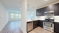 Located at 556 Colonial Rd in Franklin Lakes, New Jersey, this single-floor, 2-bedroom, 2-bathroom residence offers a thoughtfully designed layout with modern finishes throughout. The open-concept kitchen and living area serves as the heart of the home, where the kitchen impresses with dark shaker-style cabinetry, white quartz countertops, a mosaic tile backsplash, stainless steel appliances including a gas range, built-in microwave, dishwasher, and a large French door refrigerator. Stylish pendant lighting hangs above the sink, and light wood-tone flooring extends seamlessly into the bright, airy living area, which features large windows with views of lush greenery. The spacious primary bedroom includes soft carpeting and a generously sized walk-in closet with wire shelving on both sides. The primary en-suite bathroom is finished with large-format gray tile flooring, a dual-sink dark vanity with quartz countertop, a wide mirror, and a glass-enclosed walk-in shower. The second bedroom offers plush carpeting, a double-door closet, and multiple windows that fill the room with natural light. The second bathroom mirrors the refined aesthetic with matching tile, a dark vanity, and a full soaking tub with a tiled surround.