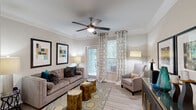 Located at 2951 Satellite Blvd in Duluth, GA, this well-appointed single-floor residence offers three bedrooms and three full bathrooms across a thoughtfully designed layout. The open-concept living area features light wood-style flooring, crown molding, and a ceiling fan, flowing seamlessly into the dining area and kitchen. The dining room is accented by a pendant light fixture, chair rail molding, and louvered closet doors, adding classic architectural detail. The kitchen is equipped with white cabinetry, granite-style countertops, stainless steel appliances including a range and built-in microwave, and a breakfast bar for casual dining. Each bedroom offers plush carpeting, ceiling fans, and windows that invite natural light and views of surrounding greenery. The primary bedroom provides a generous footprint with ample space for a large furniture arrangement. The bathrooms feature tub/shower combinations with clean white tile surrounds. A dedicated in-unit laundry area accommodates a full-size washer and dryer side by side with overhead shelving. Two closets provide additional storage throughout the home. The neutral color palette, consistent finishes, and functional layout make this a comfortable and cohesive living space.