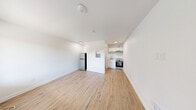 The Theodore Studio in Tacoma, WA is a thoughtfully designed studio unit that maximizes every inch of its compact footprint. The open-plan living area features light-toned hardwood-style flooring that runs throughout the space, complementing the crisp white walls and clean-lined design aesthetic. Recessed and flush-mount ceiling lighting brightens the interior, while a window with an outdoor view and a wall-mounted HVAC unit provide both natural light and climate control.

The kitchen is positioned along one wall and includes white cabinetry, a stainless steel range with oven, an under-cabinet range hood, a sink with white base cabinetry, and a full-size refrigerator. A wall-mounted electrical panel is conveniently accessible within the main living space.

The bathroom is efficiently laid out, featuring warm wood-style flooring that matches the rest of the unit, a walk-in shower stall, a toilet, and a wall-mounted sink. A frosted glass panel on the bathroom door adds a touch of privacy while maintaining a light, open feel.

Overall, The Theodore Studio presents a clean, move-in-ready environment with modern finishes, offering a functional and practical living space in Tacoma, WA.
