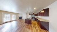 This single-floor residence offers a well-designed open-concept layout where the kitchen and living area flow seamlessly together. The kitchen is a functional centerpiece, equipped with rich dark wood cabinetry, stainless steel appliances including a gas range, microwave, refrigerator, and dishwasher, and a granite-topped island with pendant lighting overhead. Light wood-toned flooring extends throughout the main living areas, adding warmth and continuity to the space.

The living area is highlighted by a tile-surround fireplace and a wall-mounted mini-split unit, providing both comfort and climate control year-round. French doors allow natural light to filter in while offering outdoor access. The bedrooms feature neutral carpet flooring and windows with blinds that provide views of the surrounding landscape.

Two bathrooms serve the unit: one includes a vanity with dark wood cabinetry and a shower-tub combination, while the other features a sliding glass-door shower enclosure, a vanity with light countertops, and wood-style flooring. Throughout the space, neutral tones and clean finishes create a cohesive and practical living environment.