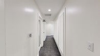 Located at Asbury Square in Dunwoody, Georgia, this single-floor community amenity space offers a generously sized, thoughtfully designed interior ideal for socializing and recreation. The layout encompasses three distinct living areas and two connecting hallways, each contributing to a cohesive yet varied spatial experience.

The main lounge area makes a bold design statement with dramatic dark accent walls, bold botanical-patterned wallpaper, and rich olive green paint. It is furnished with leather seating, a dark wood coffee table, and a wall-mounted television atop a stylish media console. Large windows dressed with dark curtains allow natural light to filter in while maintaining privacy.

A secondary living zone transitions into a bright, airy game room featuring soaring double-height ceilings and an expansive bank of windows that flood the space with natural light and offer views of the surrounding greenery. A full-length shuffleboard table anchors this area, complemented by a pool table visible from the open floor plan. Artwork and casual seating add to the relaxed atmosphere.

An additional gathering room features a round table with modern chairs, wood slat wall paneling, and abundant window light — well-suited for small group meetings or casual games. Throughout, durable carpet tile flooring in blue-grey tones unifies the design and reinforces the space's contemporary, community-oriented character.