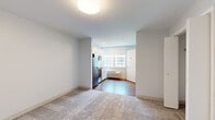 Located at 873 Harwich Road in Brewster, Massachusetts, this efficiently designed one-bedroom, one-bathroom unit offers a well-organized layout across a single floor. The living and bedroom areas are finished with soft, neutral-toned carpet, creating a warm and comfortable atmosphere throughout. The spacious primary bedroom includes an adjacent closet, providing practical storage solutions.

The kitchen is a standout feature, equipped with stainless steel appliances including a full-size refrigerator, an electric range, and a built-in microwave. White shaker-style cabinetry with brushed hardware lines the walls, complemented by a granite-look countertop and a single-basin sink. A large window fitted with a roller shade floods the kitchen with natural light and offers views of the surrounding area, while a wall-mounted PTAC unit provides climate control. The kitchen is finished with warm hardwood-style flooring, offering a clean contrast to the carpeted living spaces.

The bathroom is clean and functional, featuring wood-style flooring, a full-size soaking tub with shower, a toilet, a wall-mounted sink, and a vanity mirror with overhead lighting. The unit's neutral white walls and simple, modern finishes throughout contribute to a bright, move-in-ready aesthetic well-suited for comfortable everyday living.