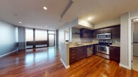 Located on the 14th floor at 400 S Fourth St in downtown St. Louis, this high-rise residence offers a compelling blend of modern design and sweeping urban scenery. The open-concept living and dining area is anchored by rich hardwood flooring that extends throughout the main living spaces, complemented by cool gray walls and recessed lighting. Floor-to-ceiling windows and a glass sliding door flood the interior with natural light while framing breathtaking panoramic views of the St. Louis skyline, the Mississippi River, and the historic Eads Bridge.

The kitchen is thoughtfully designed with dark espresso cabinetry, granite countertops, a peninsula with an under-mount sink, and a full suite of stainless steel appliances including a refrigerator, range, built-in microwave, and dishwasher. An adjacent utility area provides in-unit laundry hookups for added convenience.

The bedroom features plush carpeting, neutral tones, and access to a walk-in closet. The bathroom is well-appointed with a dual-sink vanity topped with granite, dark wood cabinetry, a large wall mirror, and a separate shower enclosure. This residence delivers a refined urban living experience in the heart of downtown St. Louis.