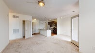 This single-floor residence offers a thoughtfully designed open-concept layout that seamlessly connects the living, dining, and kitchen areas. The spacious living area is finished with plush neutral carpeting and features a ceiling fan, while large windows and a glass door to a private balcony flood the space with natural light and provide outdoor views.

The kitchen is a standout feature, centered around a granite-topped island with an integrated sink and pendant lighting overhead. Dark espresso cabinetry provides ample storage and pairs elegantly with the granite countertops. A full suite of stainless steel appliances — including a gas range, built-in microwave, refrigerator, and dishwasher — completes the space. Track lighting and warm wood-look flooring add to the kitchen's polished, functional aesthetic.

The bedroom is a calm, carpeted retreat with a generous window dressed with blinds, allowing for natural light and privacy. The bathroom mirrors the kitchen's design language with dark cabinetry, a white countertop vanity, and clean tile flooring. A dedicated laundry room houses a full-sized washer and dryer with overhead shelving, adding everyday convenience. Throughout, the interior maintains a consistent, neutral palette that creates a bright and welcoming atmosphere.