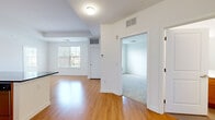 Located at 1323 Greenway Blvd in Roselle, NJ, this single-floor, two-bedroom, one-bathroom residence offers a well-designed layout with a clean, neutral aesthetic throughout. The open living area features warm hardwood flooring that flows seamlessly from the entryway through the combined living and dining space, creating a bright and cohesive feel. Natural light enters through sizable windows fitted with blinds, offering views of the surrounding neighborhood.

The kitchen is efficiently designed with rich wood cabinetry, dark granite countertops, and a full suite of stainless steel appliances including a refrigerator, gas range, and built-in microwave. Track lighting illuminates the kitchen area, and a peninsula counter provides a convenient pass-through to the living space.

Both bedrooms are carpeted and finished with crisp white walls. The spacious primary bedroom includes a walk-in closet with built-in shelving, while the second bedroom benefits from a large window that draws in ample natural light. The full bathroom is finished with classic white subway tile surrounding a soaking tub and shower combination, complemented by chrome fixtures and tile flooring. The overall design is clean, functional, and move-in ready.