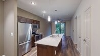 This contemporary 640 square foot apartment in Austin, TX offers a blend of style and functionality. The open-concept design seamlessly integrates the living room and kitchen, creating a spacious feel. The kitchen boasts dark wood cabinetry, stainless steel appliances, and a large island with a sink, perfect for meal prep and casual dining.

Both bedrooms feature plush carpeting and ceiling fans, with the primary bedroom spanning a generous 170 square feet. Large windows in the bedrooms provide ample natural light and scenic views. The bathroom is well-appointed with a shower/tub combination and modern fixtures.

Throughout the apartment, wood-look flooring adds warmth and durability. A private balcony accessible from the living area offers outdoor space for relaxation. The unit includes a closet for additional storage.

Thoughtful lighting, including recessed lights and pendant fixtures, enhances the modern ambiance. The apartment's neutral color palette provides a blank canvas for personalization, while its efficient layout maximizes the use of space in this urban dwelling.