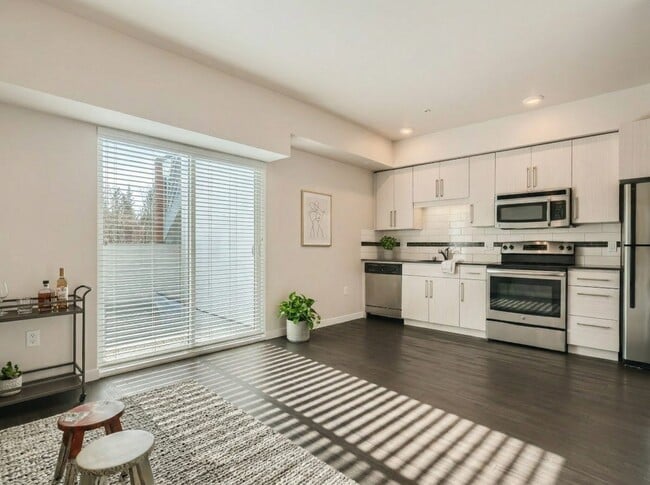 Open-concept layout featuring a modern kitchen with stainless steel appliances, dark flooring, and sliding door access at 306 Queen Anne. - 306 Queen Anne