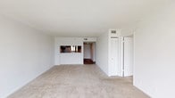 This single-floor residence offers a clean, functional layout with a neutral palette of white walls and textured ceilings throughout. The living area is generously sized, finished with wall-to-wall carpet and connected to the kitchen via a pass-through window that enhances the open feel of the space. The kitchen is well-appointed with dark espresso cabinetry, granite-look countertops, a mosaic tile backsplash, and hardwood-style flooring. White appliances include a coil-top electric range, refrigerator, dishwasher, and range hood. A louvered closet door near the kitchen entry adds a classic touch.

The two bedrooms are carpeted and bright, each featuring sliding windows that frame outdoor views of trees and palm-lined surroundings, filling the rooms with natural light. The primary bathroom includes a wide vanity with white cabinetry, a large mirror, and Hollywood-style lighting, with a separate louvered storage closet nearby. The second bathroom offers a full tub-shower combination with white tile surround and a single vanity. The overall ambiance is light, neutral, and move-in ready.