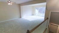 This three-floor home offers a well-organized and functional layout across multiple levels, providing ample space for comfortable living. The main living area is a standout feature, showcasing a generously sized, open-plan room with soft, wall-to-wall carpeting that adds warmth and comfort underfoot. Neutral tones throughout the space create a clean, inviting atmosphere that is easy to personalize.

A large sliding glass door serves as a focal point in the living area, flooding the room with natural light and offering direct views of the surrounding greenery and outdoor landscape. This seamless connection between the interior and exterior enhances the overall sense of openness and airiness. The room's layout is versatile, easily accommodating a variety of furniture arrangements.

A classic wooden staircase with a traditional banister connects the floors, adding a timeless architectural detail to the home. The staircase design is both functional and visually appealing, contributing to the home's traditional character.

The neutral wall palette and consistent flooring choices throughout create a cohesive flow from room to room and floor to floor. Overall, this home presents a bright, well-maintained environment with a welcoming ambiance suited for everyday living.