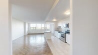 Located at 25 Cougar Crt in Toronto's Scarborough neighbourhood, this well-appointed 2-bedroom, 1-bathroom unit offers a generous and thoughtfully laid-out floor plan. Classic parquet wood flooring flows consistently throughout the living spaces and bedrooms, lending warmth and character to the clean, white-walled interiors.

The open-concept kitchen has been tastefully renovated, featuring crisp white shaker-style cabinetry, dark countertops, a white subway tile backsplash, and a full suite of stainless steel appliances including a refrigerator, range, microwave, and dishwasher. Light porcelain tile flooring completes the kitchen's modern aesthetic. Adjacent to the kitchen, the spacious living room is flooded with natural light through a wide bank of floor-to-ceiling windows, offering pleasant views of the surrounding greenery and Toronto skyline beyond.

The primary bedroom is generously sized with a large window framing treetop views, while the second bedroom is equally bright and versatile. Both rooms benefit from access to multiple closets. The bathroom features clean white subway tile surrounding a full soaker tub and shower, with a simple, functional design. A welcoming hallway connects all areas of the unit, completing this bright and practical home.