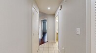 This single-floor residence offers a thoughtfully designed layout with a clean, modern aesthetic. Rich, dark hardwood flooring flows through the main living areas and bedrooms, complemented by neutral gray walls and white trim that create a bright, cohesive interior. The kitchen is a standout feature, outfitted with dark espresso cabinetry, granite countertops, a white tile backsplash, and a full suite of stainless steel appliances including a range, microwave, refrigerator, and dishwasher. A tile-floored hallway connects the living spaces to the private quarters, with a full bathroom accessible along the corridor. The primary bathroom is generously sized, featuring white tile flooring, a dark-toned vanity with a granite countertop, a soaking tub, and a glass-enclosed shower. Bedrooms are well-proportioned and filled with natural light through large windows fitted with horizontal blinds, offering impressive views of the city skyline and surrounding greenery. A ceiling fan adds comfort to the main bedroom. Closet space is ample, with walk-in closets featuring wire shelving systems for organized storage. Recessed lighting and a clean, contemporary color palette give the entire space a polished, move-in-ready feel.
