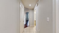 This single-floor residence offers a thoughtfully designed layout with a clean, modern aesthetic. Rich, dark hardwood flooring flows through the main living areas and bedrooms, complemented by neutral gray walls and white trim that create a bright, cohesive interior. The kitchen is a standout feature, outfitted with dark espresso cabinetry, granite countertops, a white tile backsplash, and a full suite of stainless steel appliances including a range, microwave, refrigerator, and dishwasher. A tile-floored hallway connects the living spaces to the private quarters, with a full bathroom accessible along the corridor. The primary bathroom is generously sized, featuring white tile flooring, a dark-toned vanity with a granite countertop, a soaking tub, and a glass-enclosed shower. Bedrooms are well-proportioned and filled with natural light through large windows fitted with horizontal blinds, offering impressive views of the city skyline and surrounding greenery. A ceiling fan adds comfort to the main bedroom. Closet space is ample, with walk-in closets featuring wire shelving systems for organized storage. Recessed lighting and a clean, contemporary color palette give the entire space a polished, move-in-ready feel.