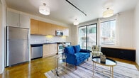 Located at 2245 3rd St, Unit E307, in San Francisco's dynamic Mission Bay neighborhood, this contemporary residence offers a thoughtfully designed open-plan layout that seamlessly connects the living and kitchen areas. Distinctive polished concrete floors in a rich amber tone run throughout the main living space, lending an urban, loft-inspired character to the interior.

The kitchen is fitted with warm-toned flat-front cabinetry, dark granite countertops, a white subway tile backsplash, and a full suite of stainless steel appliances including a gas range, dishwasher, microwave, refrigerator, and an in-unit washer. The space is efficient yet well-appointed for everyday living.

The open living area benefits from abundant natural light streaming through large floor-to-ceiling windows and a sliding glass door that opens onto a private balcony, offering views of the surrounding cityscape. Track lighting and pendant fixtures complement the clean, modern aesthetic throughout.

The bathroom features large-format light tile flooring, white subway tile walls, an open walk-in shower, and a streamlined wood-framed vanity with an integrated sink, maintaining the residence's contemporary design language. Clean white walls and a neutral palette throughout the unit create a bright, versatile backdrop well-suited to urban living.