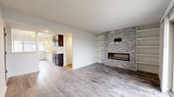 This thoughtfully designed single-floor residence offers two bedrooms and a functional, open layout that makes efficient use of its space. The combined kitchen and living area serves as the heart of the home, where a standout stacked-stone accent wall frames a sleek linear fireplace flanked by built-in white shelving — creating a bold yet refined focal point. The living area features wood-look luxury vinyl plank flooring and a sliding glass door that opens to a private balcony, filling the space with natural light and outdoor views.

The kitchen is well-equipped with dark espresso cabinetry, stainless steel appliances, marble-look countertops, a peninsula island with an undermount sink, and pendant lighting overhead. A dedicated pantry closet and tile backsplash add both practicality and polish.

Both bedrooms are finished with plush carpet flooring and ceiling fans, offering a comfortable and quiet retreat. The primary bedroom is generously sized, while the second bedroom also provides ample room. One bedroom features a large window with tree-lined views, and both rooms include closet access. The neutral color palette throughout the residence creates a clean, cohesive ambiance suited for a variety of interior styles.