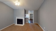 Located at 4720 Reading Rd in Rosenberg, Texas, this single-story home offers a well-organized layout with a warm, neutral aesthetic throughout. The living room serves as a central gathering space, highlighted by a white brick fireplace, vaulted ceilings that add a sense of openness, and plush carpeting underfoot. A ceiling fan provides added comfort, while the room flows naturally toward the kitchen area via a pass-through counter.

The kitchen is equipped with white cabinetry offering generous storage, speckled laminate countertops, and a full suite of white appliances including an electric range, dishwasher, and refrigerator. Dark hardwood-style flooring grounds the space, and a glass door with blinds provides access to the exterior, allowing natural light to fill the room.

The bedrooms continue the home's soft gray color palette, each featuring carpet, ceiling fans or light fixtures, and windows with blinds that invite natural light. The primary bedroom benefits from vaulted ceilings and direct access to a private en-suite bathroom. Additional bedrooms are well-proportioned with ample wall space and connectivity to the hallway. The home's cohesive design, consistent finishes, and practical floor plan make it a functional and inviting single-floor residence.