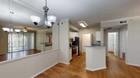 Located at 900 Meadow Creek Dr in Irving, TX, this one-bedroom, one-bathroom unit offers a thoughtfully arranged single-floor layout. Warm hardwood-style flooring runs throughout the space, lending a cohesive and inviting feel to every room.

The open living and dining area is anchored by a decorative chandelier and features a large mirrored wall that enhances the sense of space and reflects natural light. A sliding glass door with vertical blinds opens to a private balcony, offering views of the surrounding landscaped exterior.

The kitchen is designed for functionality, featuring white cabinetry, granite-style countertops, stainless steel appliances including a refrigerator, range, and microwave, and a peninsula that provides additional prep and serving space. Crown molding and a textured ceiling add architectural character throughout the common areas.

The bedroom is a well-sized retreat with hardwood-style flooring, neutral walls, and a dedicated closet for storage. A hallway connects the main living spaces to the bedroom and bathroom.

The bathroom includes a full tub-shower combination with a classic blue tile accent border, granite-style countertops, and wood-style flooring, completing this efficiently designed Irving residence.